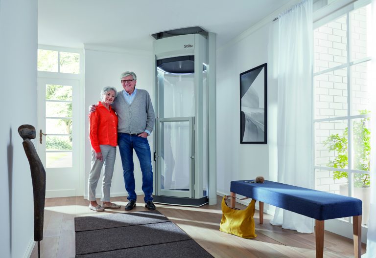 Two people standing beside a modern home elevator in a bright residential space.