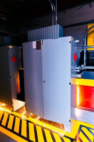 Commercial elevator controller cabinets and equipment arranged in a machine room with back lighting.